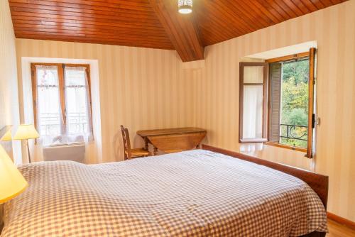 une chambre avec un lit et une table et deux fenêtres dans l'établissement Clevacances 2 cles 4 personnes a pont ravagers, à Sainte-Croix-Vallée-Française