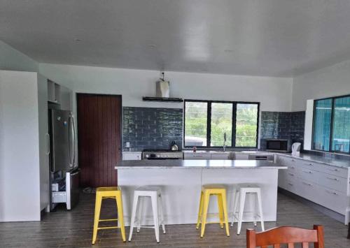 a kitchen with a white counter and yellow stools at Mama MIREKA Homestay in Arorangi