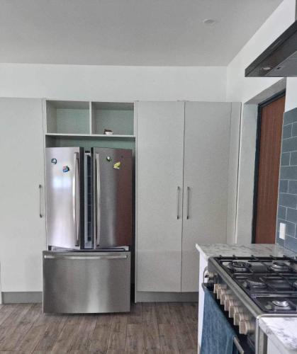 a kitchen with a stainless steel refrigerator and cabinets at Mama MIREKA Homestay in Arorangi