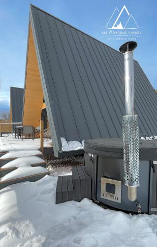 a snow covered roof with a fireplace on a house at Les Atypiques Chalets in Barbey-Séroux