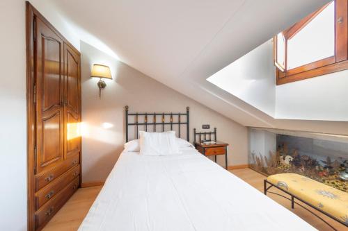 a bedroom with a large white bed in a attic at Hostal SIN RECEP24H Puerta de la Villa - Pet friendly & Restaurante in Almazán