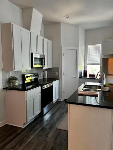 a kitchen with white cabinets and black counter tops at Peaceful Vacation Spot with Modern Touches and Amazing Ambiance in Leander