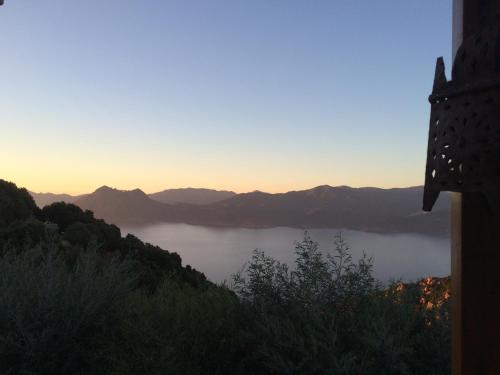 a view of a lake with the sun setting over the mountains at Casa Mimosa in Piana