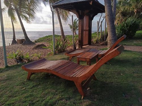 una panchina di legno e un gazebo sulla spiaggia di Triplex 3 Suítes 10 PESSOAS Cond Aldeia dos Pescadores Praia do Forte a Praia do Forte