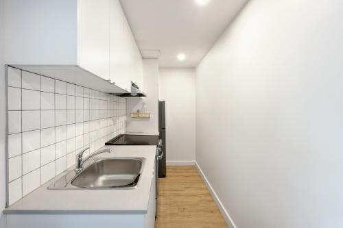 a kitchen with a sink and white cabinets at Appartements Dorchester in Montreal