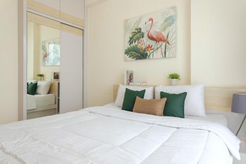 a bedroom with a large white bed with green pillows at Calma 1BR I at TreePark Apartment in Dadap