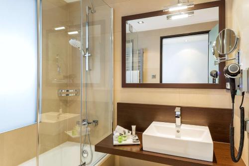 a bathroom with a sink and a shower at NH Collection Dresden Altmarkt in Dresden
