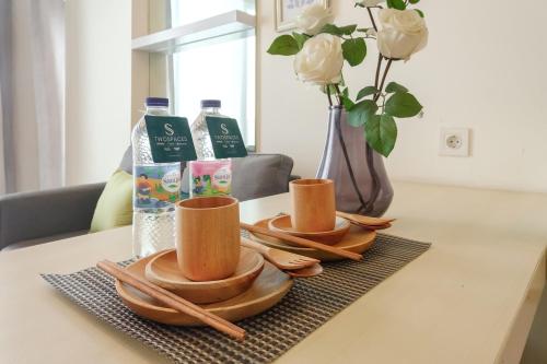 a table with plates and spoons and a vase with flowers at Calma 1BR I at TreePark Apartment in Dadap