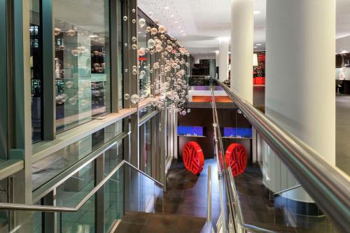 a glass corridor with red chairs in a building at NH Collection Dresden Altmarkt in Dresden
