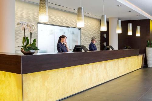 two women sitting at a reception counter in a office at NH Collection Dresden Altmarkt in Dresden