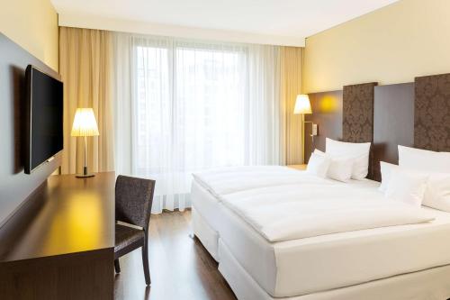 a bedroom with a large white bed and a television at NH Collection Dresden Altmarkt in Dresden