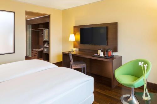 a hotel room with a bed and a desk with a television at NH Collection Dresden Altmarkt in Dresden