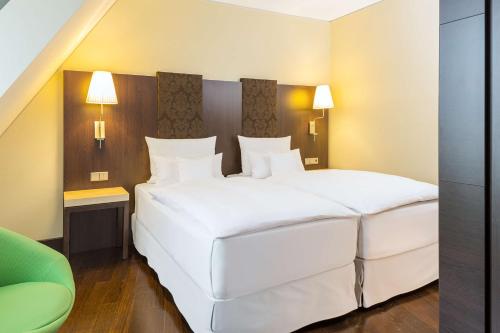 a bedroom with two large white beds in it at NH Collection Dresden Altmarkt in Dresden