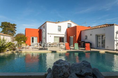 une piscine en face de deux bâtiments avec des tons orange et blanc dans l'établissement Spacious 210 m villa in Cap d’Agde!, au Cap d'Agde