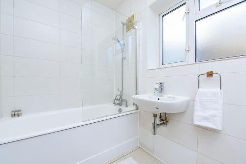 a white bathroom with a sink and a bath tub at Split Level 2 Bed Apartment- Mayfair in London