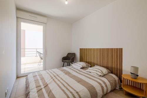 une chambre avec un grand lit et un balcon dans l'établissement Le Sunny - Appt climatisé avec piscine, à Saint-Raphaël