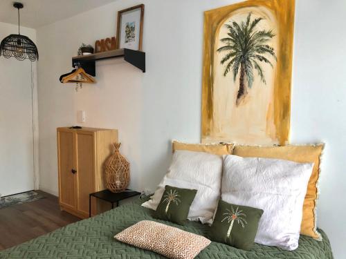 une chambre avec un lit avec une peinture de palmier sur le mur dans l'établissement STUDIO COSY PROCHE DISNEY, à Chalifert