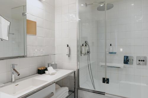 a white bathroom with a shower and a sink at Boutet Bastille Hotel Paris - MGallery Collection in Paris