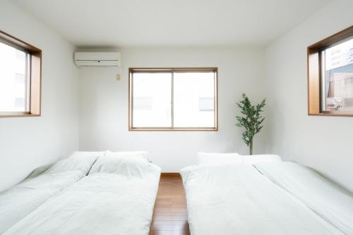 two beds in a white room with windows at LN23 神戸三宮駅と新神戸駅から交通至便3LDK憩House in Kobe