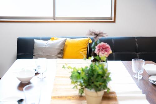 a dining room table with glasses and flowers on it at LN23 神戸三宮駅と新神戸駅から交通至便3LDK憩House in Kobe