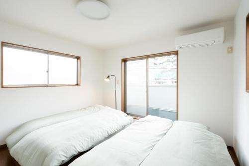 two beds in a room with two windows at LN23 神戸三宮駅と新神戸駅から交通至便3LDK憩House in Kobe