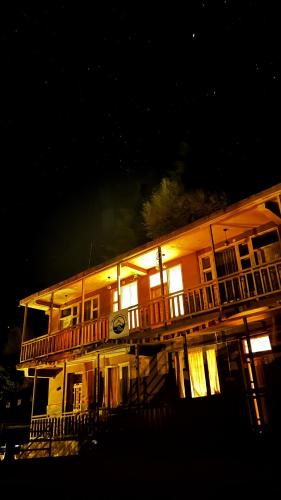 a large wooden house with a deck at night at Happy Returns Home, Jibhi in Jibhi