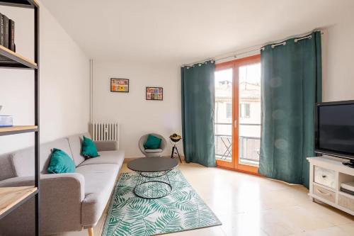 un salon avec un canapé et une télévision dans l'établissement Les Arènes, 30m des Arènes, Balcon, Clim, à Nîmes