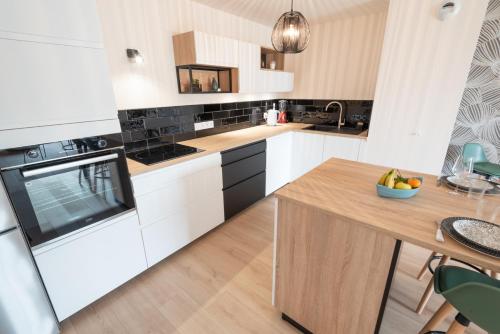 a kitchen with white cabinets and a wooden table at Elégant Appartement 2 chambres bord de mer par Groom in Ploemeur