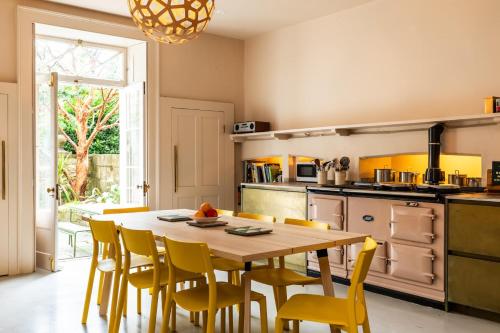 a kitchen with a wooden table and yellow chairs at Grand Georgian Townhouse with Garden in Bath