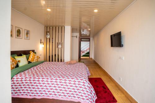 a bedroom with a bed and a tv on a wall at Monratino Himadrie -2 mins walk from Mall Road - All rooms have Kanchenjunga Mountain View in Darjeeling