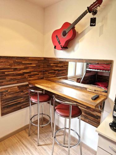 - une cuisine avec un comptoir en bois et une guitare sur le mur dans l'établissement 06 - Très joli 2 pièces neuf climatisé pour 1 à 4 personnes avec 3 lits, vue sur jardin, parking privatif gratuit, grand fourgon possible, tout le linge de maison est fourni, à Razac-sur-lʼIsle