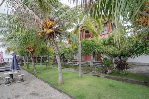 a group of palm trees in front of a building at Rommeo Inn Lovina Mitra RedDoorz in Temukus