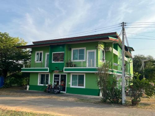 a green house with a motorcycle parked in front of it at ท่าช้างรีสอร์ท กาญจนบุรี in Kanchanaburi