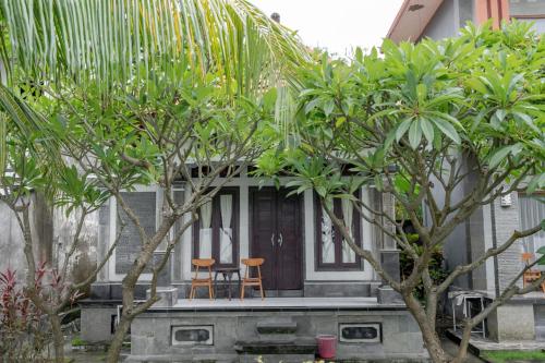 a house with two chairs on a porch with trees at Rommeo Inn Lovina Mitra RedDoorz in Temukus