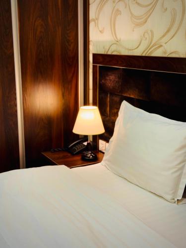 a bed with a pillow and a lamp on a table at ARK BILLUR HALAL Hotel in Tashkent