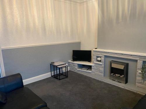 a living room with a fireplace and a television at Spacious 4 Bedroom Townhouse in Leeds