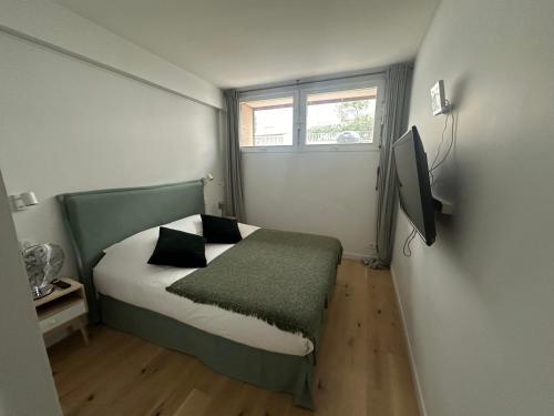 une petite chambre avec un lit et une fenêtre dans l'établissement Surcouf appartements, à Paris