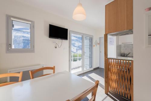 une cuisine et une salle à manger avec une table et des chaises blanches dans l'établissement Chalet de Sers, à Sers