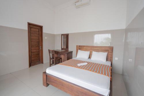 a bedroom with a bed and a desk in it at Rommeo Inn Lovina Mitra RedDoorz in Temukus