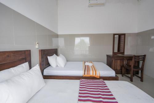 a small bedroom with two beds and a desk at Rommeo Inn Lovina Mitra RedDoorz in Temukus
