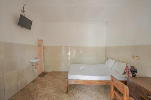 a bedroom with a white bed and a television at Rommeo Inn Lovina Mitra RedDoorz in Temukus