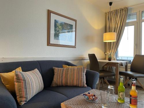 a living room with a blue couch and a table at Klaar Kiming 5c, Sandwall in Wyk auf Föhr