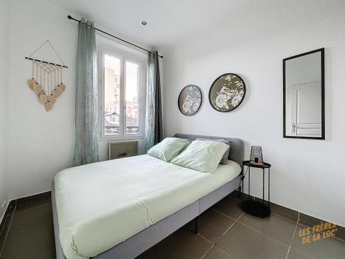 - une chambre avec un lit et 2 réveils sur le mur dans l'établissement Le Soleil Marseillais - Confort & Central - Les Frères de la Loc', à Marseille