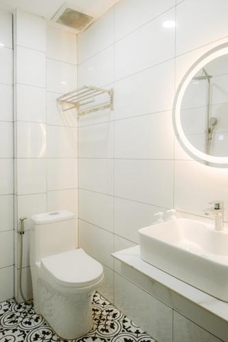 a white bathroom with a toilet and a sink at De Rivé Homestay Cần Thơ in Can Tho