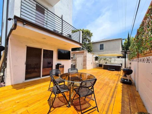 a patio with a glass table and chairs on a wooden floor at 3 bedroom with Hot Tub and Video game console 10 minutes from Rodeo Drive Beverly Hills in Los Angeles