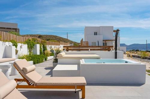 a patio with chairs and a hot tub on a house at Milos Zen Suites in Adamas