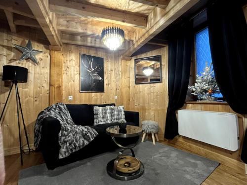 a living room with a black couch and wooden walls at La Petite Maison in Gérardmer