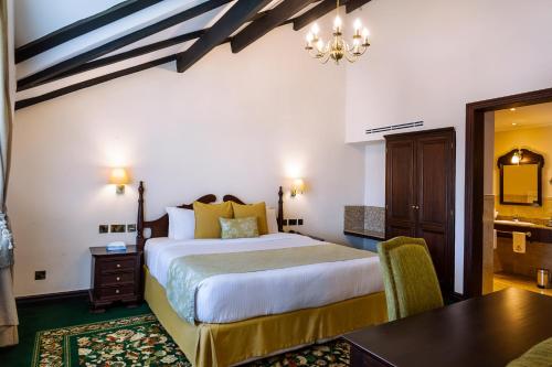 a hotel room with a bed and a desk and a table at Midland Hotel Nakuru in Nakuru