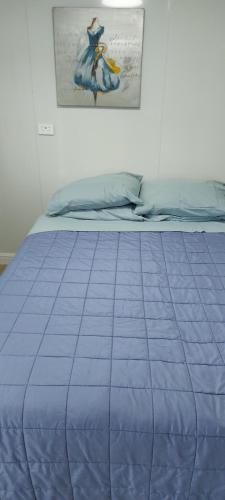 a bed with a blue comforter in a bedroom at Haley's cabin in Tauranga
