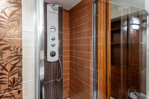 a shower in a bathroom with brown tiles at Elegantis Purificazione Suite Apartment in Rome